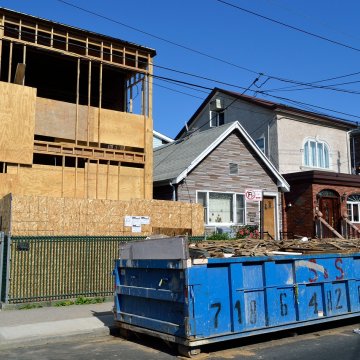 a garbage dumpster in front of a house being rebuilt
